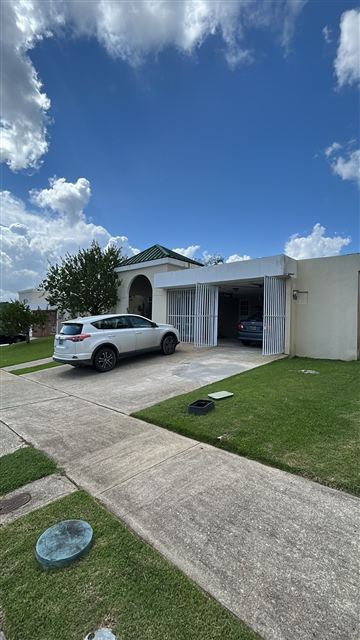 Frente de la casa con marquesina para dos autos y entrada pavimentada